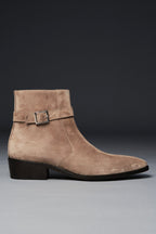 Beige suede ankle boot with a buckle on a gray background