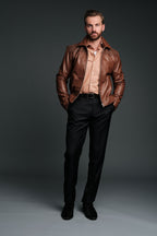 Man wearing a brown leather jacket and black pants against a gray background