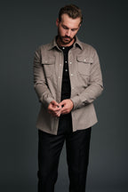 Man wearing a gray jacket over a black shirt on a dark background