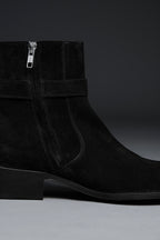 Black suede ankle boot with a zipper on a gray background