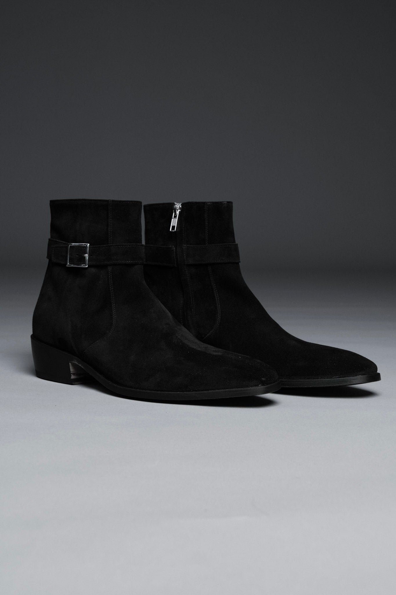 Pair of black suede ankle boots on a gray background
