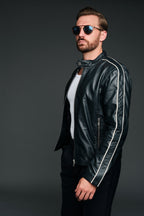 Man wearing a navy leather jacket with white stripes on a dark background