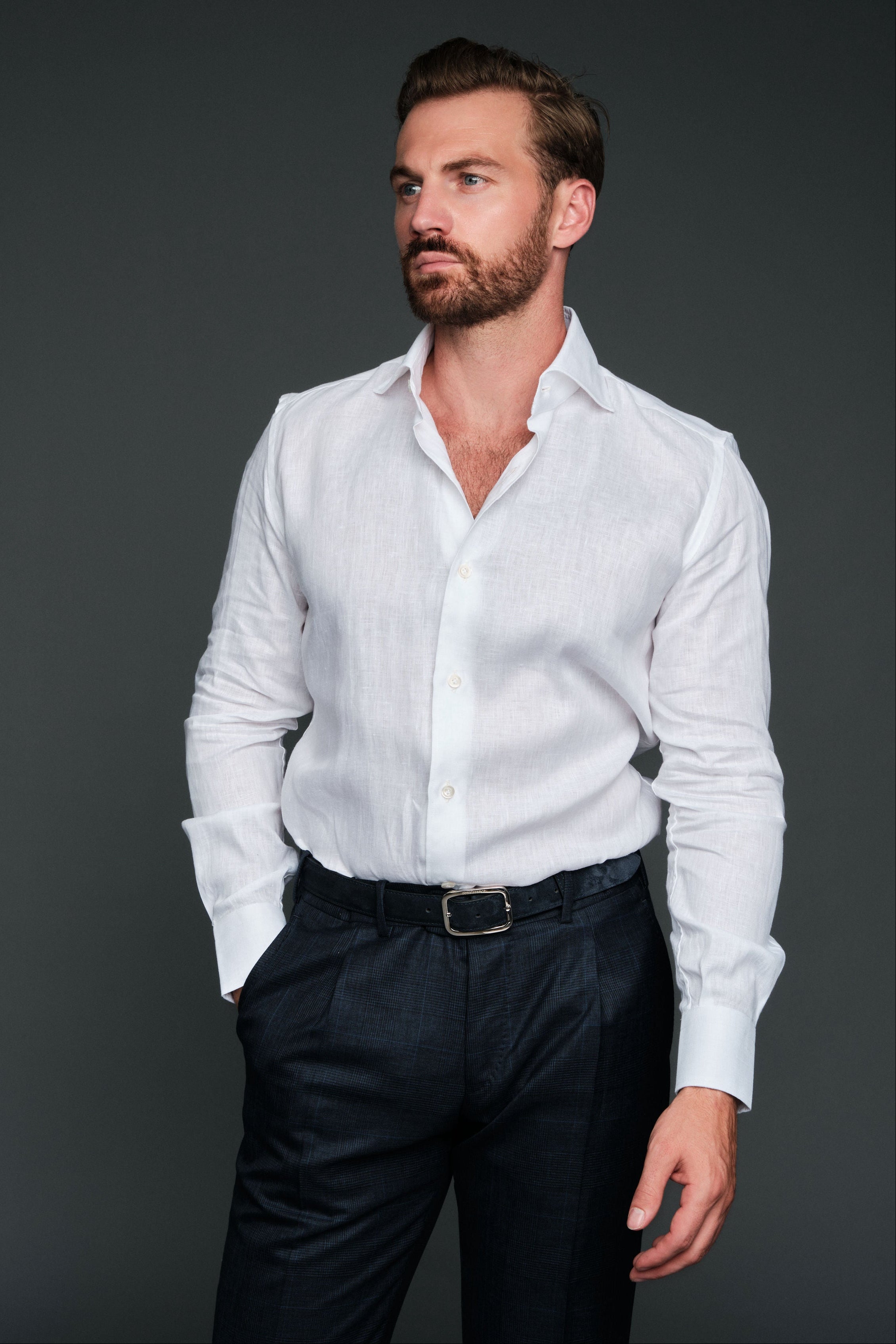 Man wearing a white shirt and dark pants against a gray background