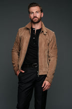 Man wearing a brown suede jacket over a black shirt on a dark background