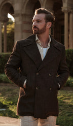 Man wearing a dark coat standing in front of architectural arches