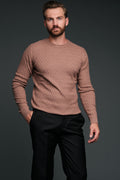 Man wearing a brown sweater and black pants against a dark background