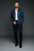 Man wearing a navy jacket, white shirt, and black pants against a gray background