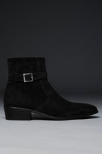 Black suede ankle boot with a buckle on a gray background