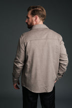 Man wearing a beige jacket against a dark background