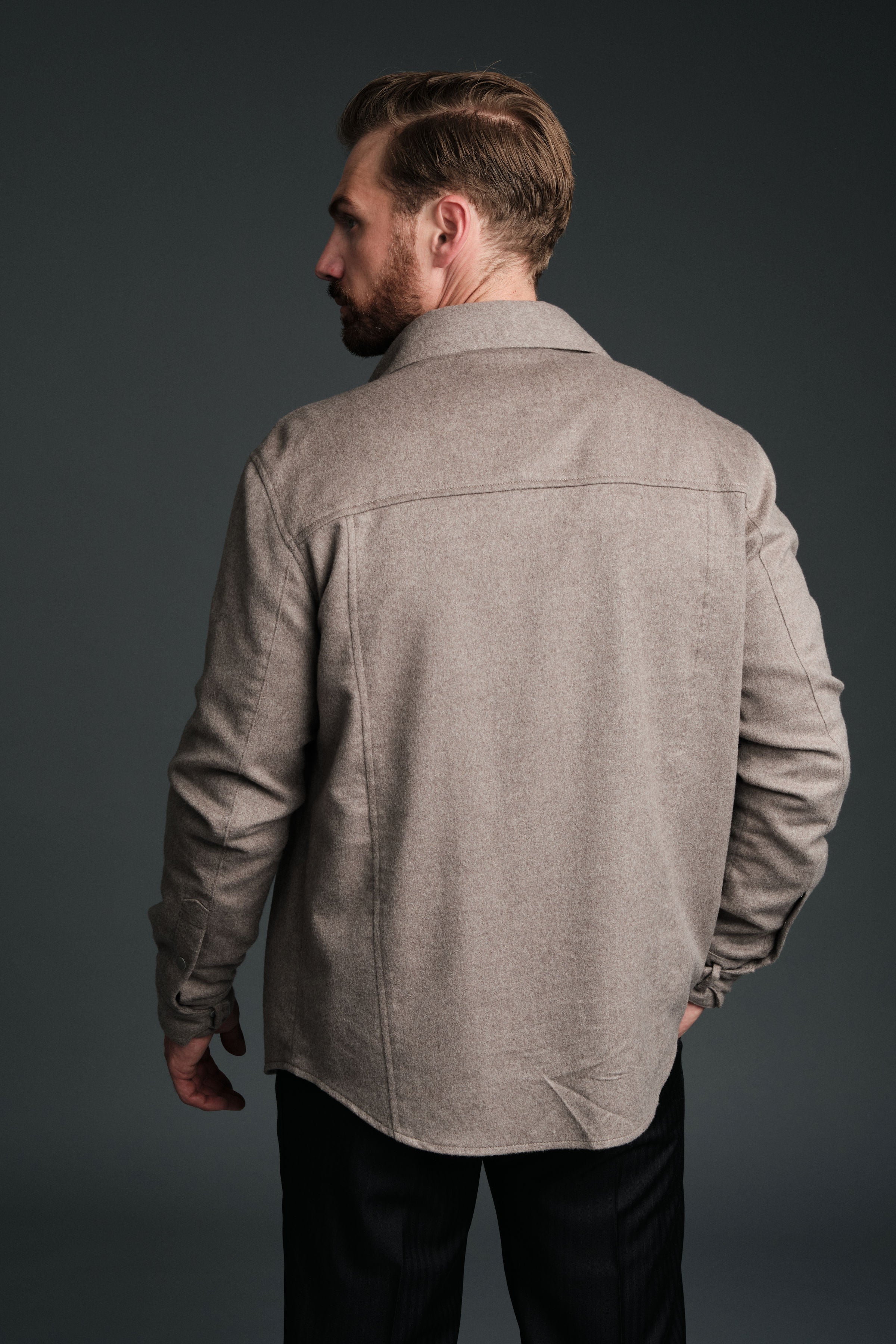 Man wearing a beige jacket against a dark background