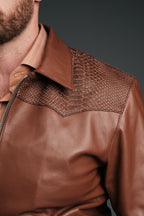 Brown leather jacket with textured shoulder detail on a dark background