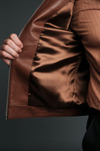 Brown leather jacket held open against a dark background