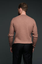 Man wearing a brown textured sweater and black pants against a dark background