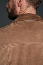 Close-up of a brown suede jacket with a dark background