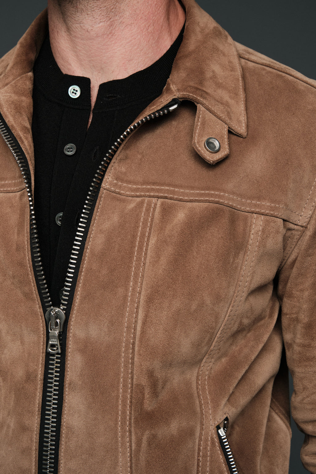 Close-up of a brown suede jacket with a zipper