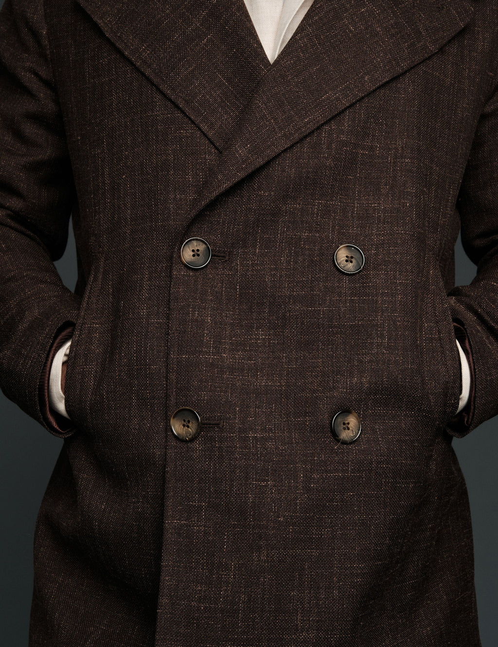 Brown double-breasted coat with visible buttons on a dark background