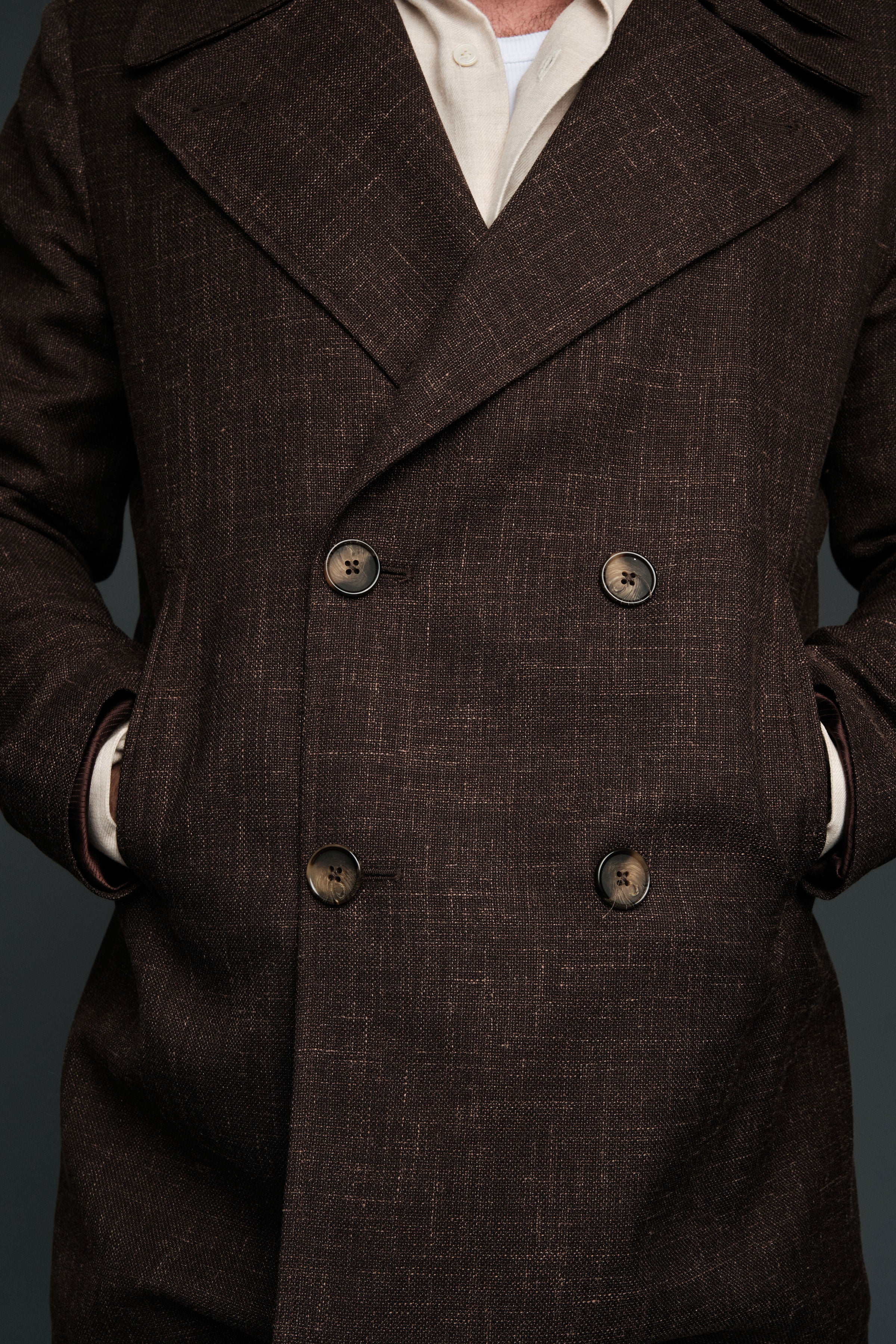 Brown double-breasted coat with visible buttons on a dark background