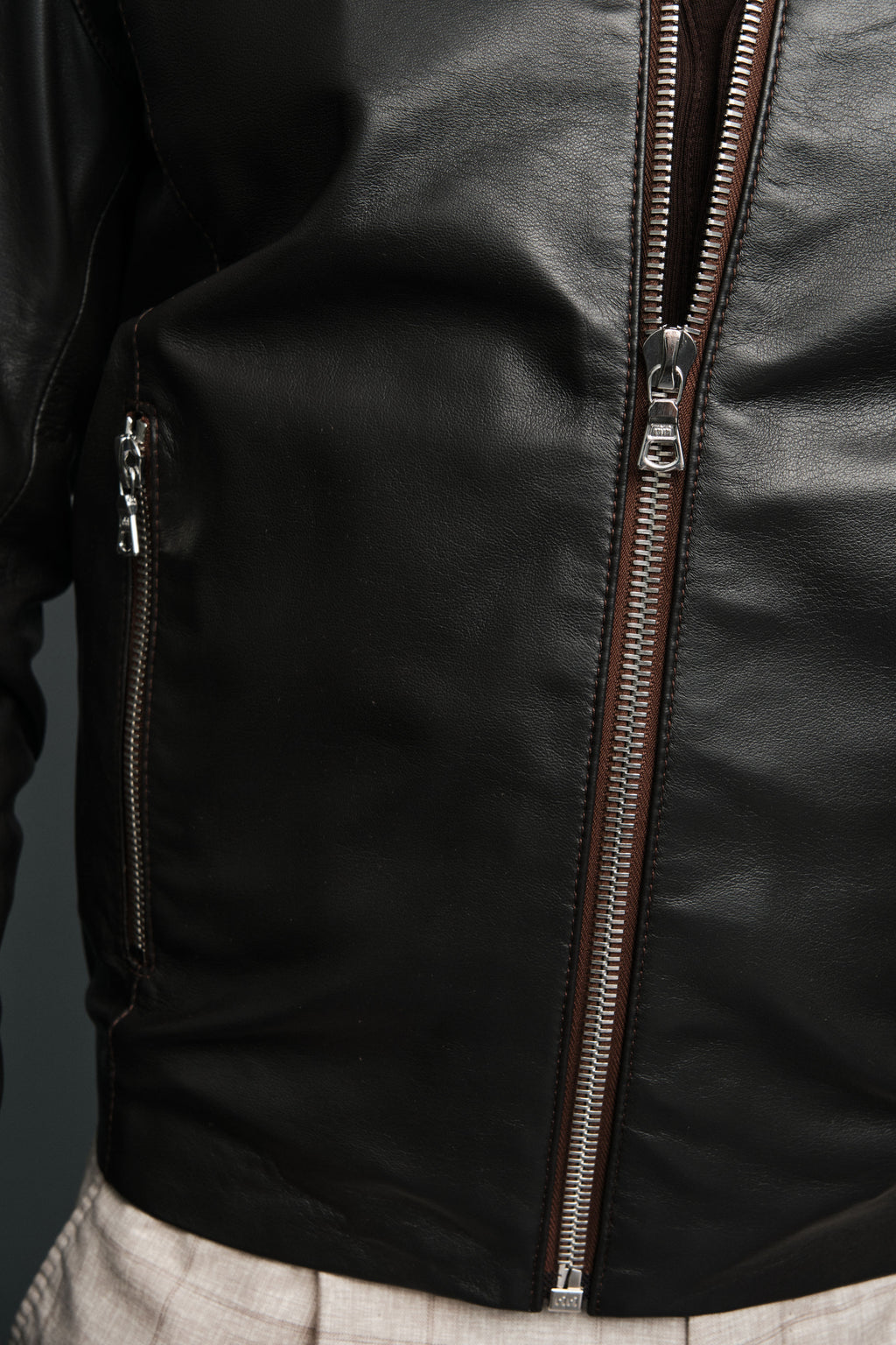 Close-up of a black brown leather jacket with zipper details on a dark background