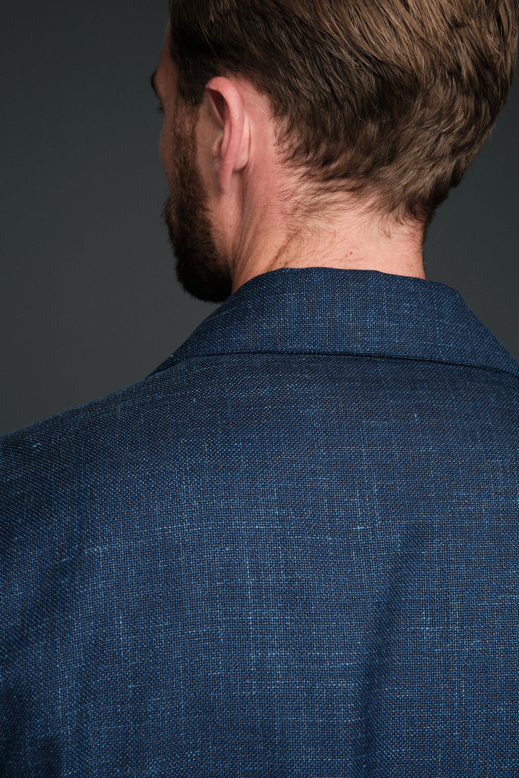 Man wearing a blue textured jacket against a gray background