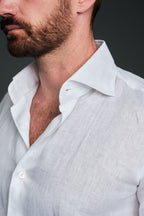 Close-up of a man wearing a white shirt with a white collar against a dark background
