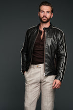 Man wearing a brown leather jacket with white stripes on a dark background
