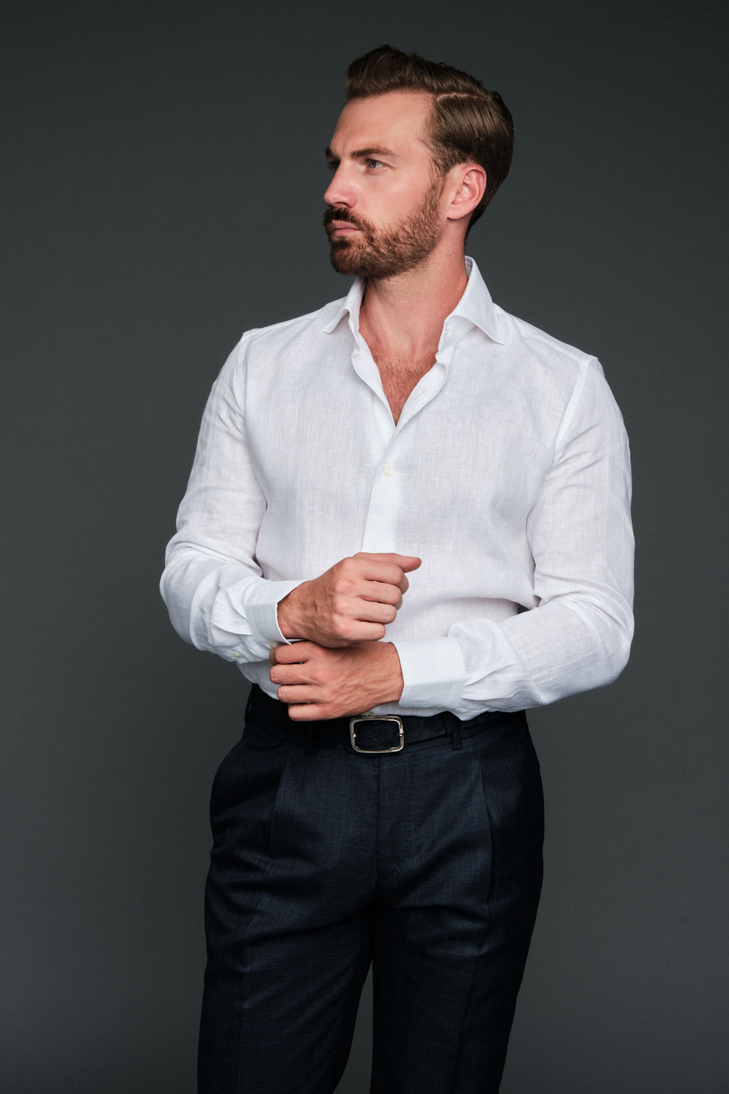 Man wearing a white shirt and dark pants against a gray background