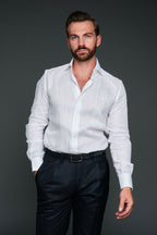 Man wearing a white dress shirt and dark pants against a gray background
